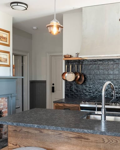 Kitchen with black tile backsplash and copper pans